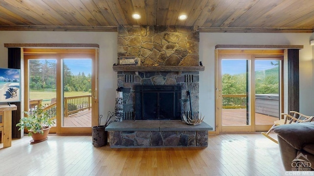 living room with wood ceiling, a stone fireplace, crown molding, and wood-type flooring