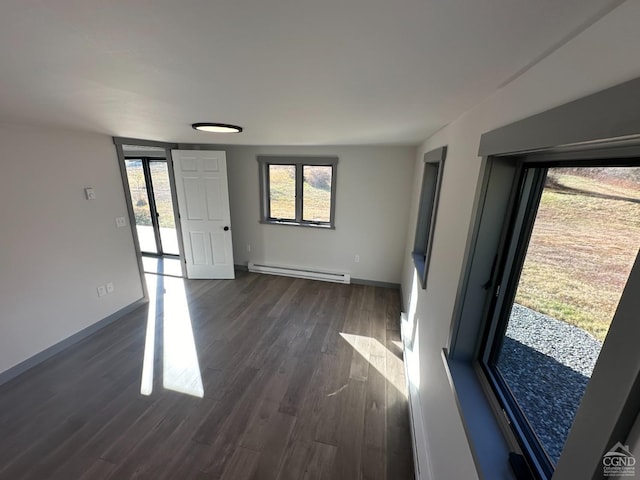 interior space with dark wood-type flooring, baseboard heating, a wealth of natural light, and baseboards