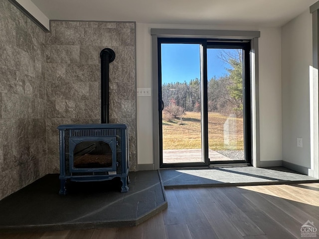 entryway featuring a wood stove, baseboards, and wood finished floors