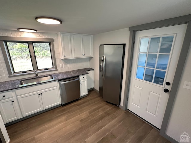 kitchen with stainless steel appliances, white cabinets, a sink, and decorative backsplash