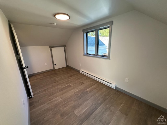 additional living space with a baseboard radiator, baseboards, vaulted ceiling, and wood finished floors