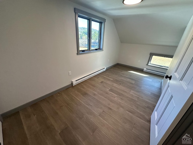 additional living space featuring a baseboard radiator, vaulted ceiling, baseboards, and wood finished floors