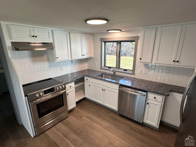 kitchen featuring dark wood finished floors, stainless steel appliances, white cabinets, a sink, and under cabinet range hood