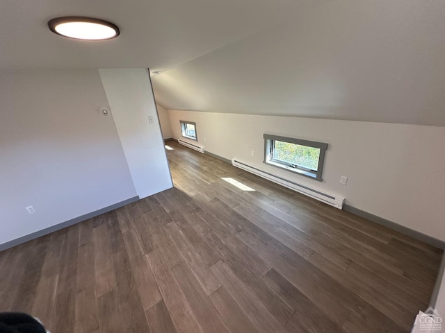 additional living space with dark wood-style floors, baseboards, a baseboard heating unit, and vaulted ceiling