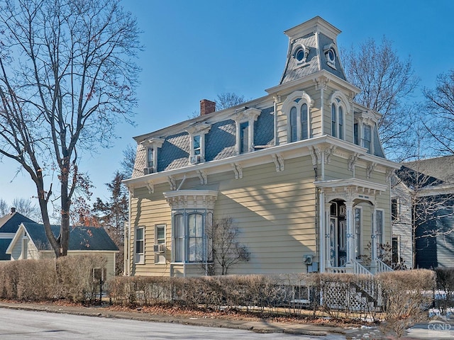 view of front facade featuring a chimney and mansard roof