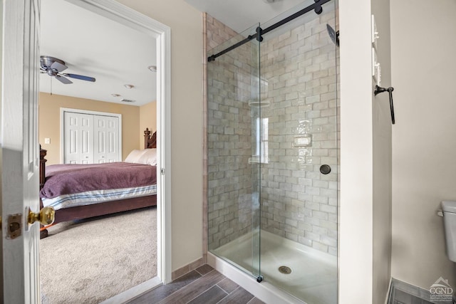 bathroom with toilet, ceiling fan, and a shower with shower door