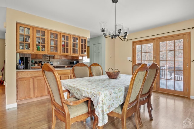 dining room with light hardwood / wood-style floors, french doors, and an inviting chandelier