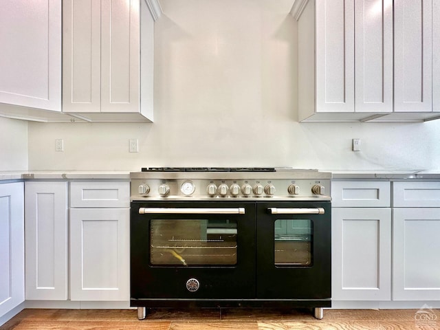 kitchen with white cabinets, stove, and light wood-type flooring