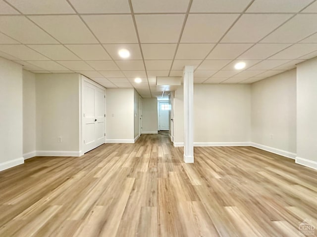 basement with a paneled ceiling and light hardwood / wood-style flooring