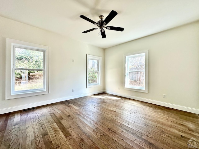 spare room with ceiling fan, a healthy amount of sunlight, and wood-type flooring