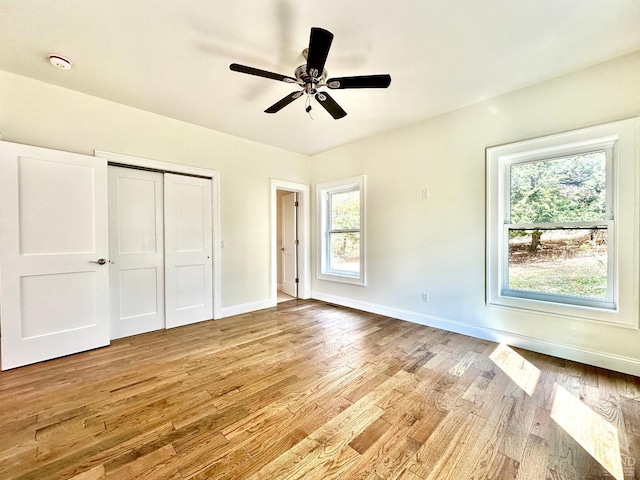 unfurnished bedroom with ceiling fan, a closet, light wood-type flooring, and multiple windows