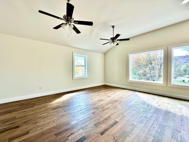 spare room with ceiling fan, a healthy amount of sunlight, vaulted ceiling, and hardwood / wood-style flooring