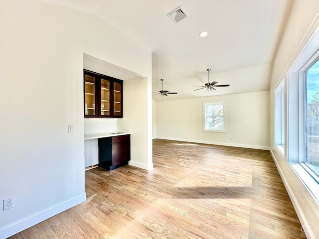 unfurnished living room featuring ceiling fan, lofted ceiling, built in desk, and light hardwood / wood-style flooring