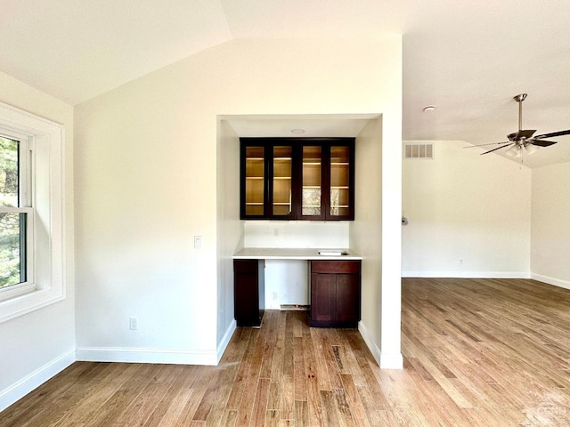 bar featuring vaulted ceiling, ceiling fan, light wood-type flooring, built in desk, and dark brown cabinetry