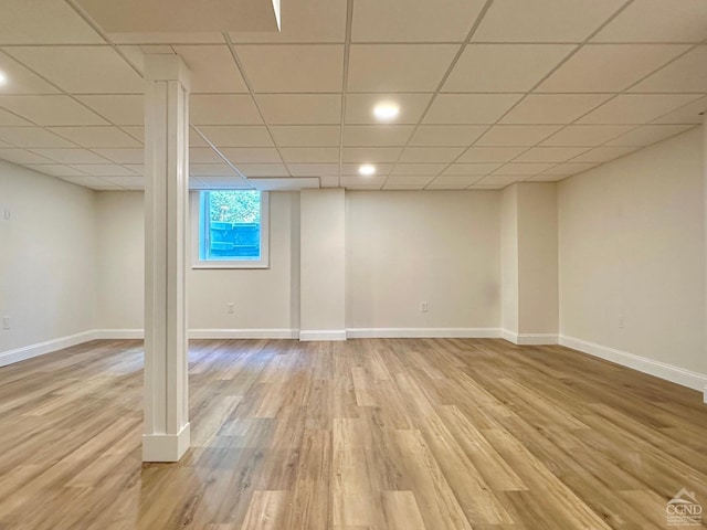 basement with a paneled ceiling and light hardwood / wood-style floors