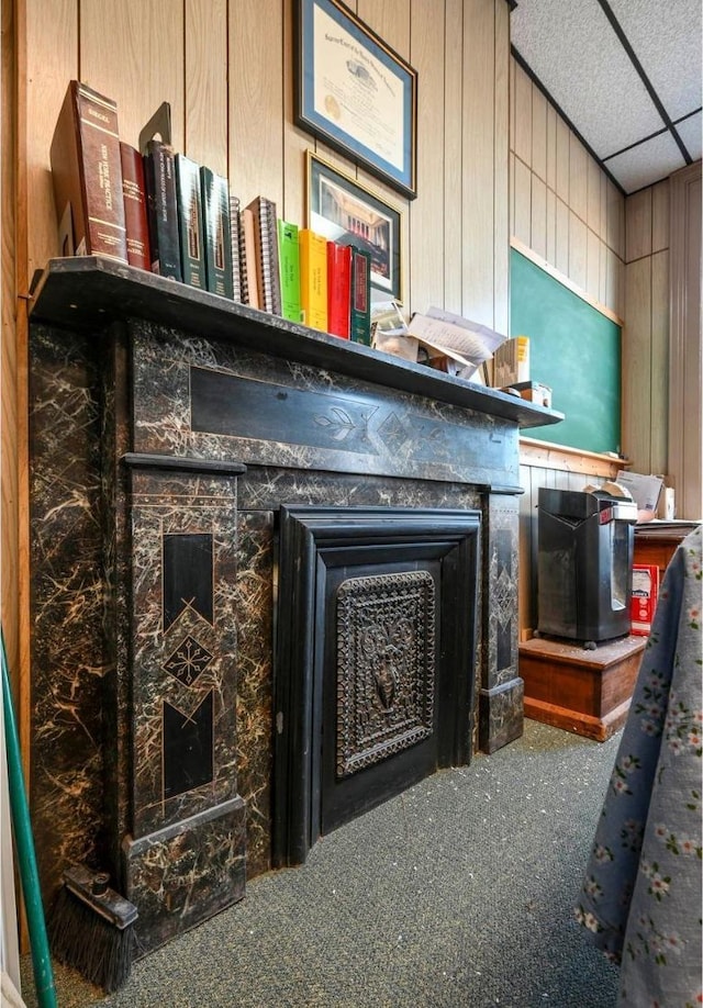 interior details with wood walls, carpet flooring, and a drop ceiling