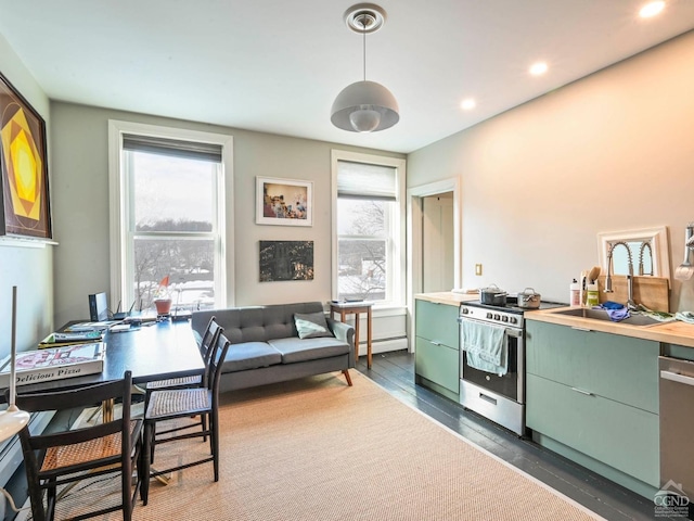 kitchen featuring butcher block counters, sink, green cabinetry, baseboard heating, and stainless steel appliances