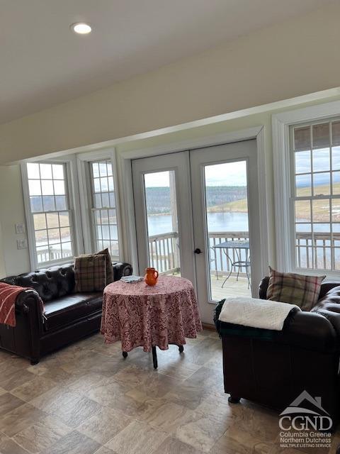 living room with a wealth of natural light, french doors, and a water view