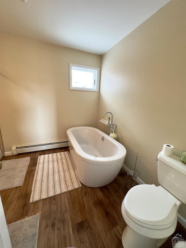full bathroom with toilet, a baseboard heating unit, wood finished floors, baseboards, and a freestanding bath