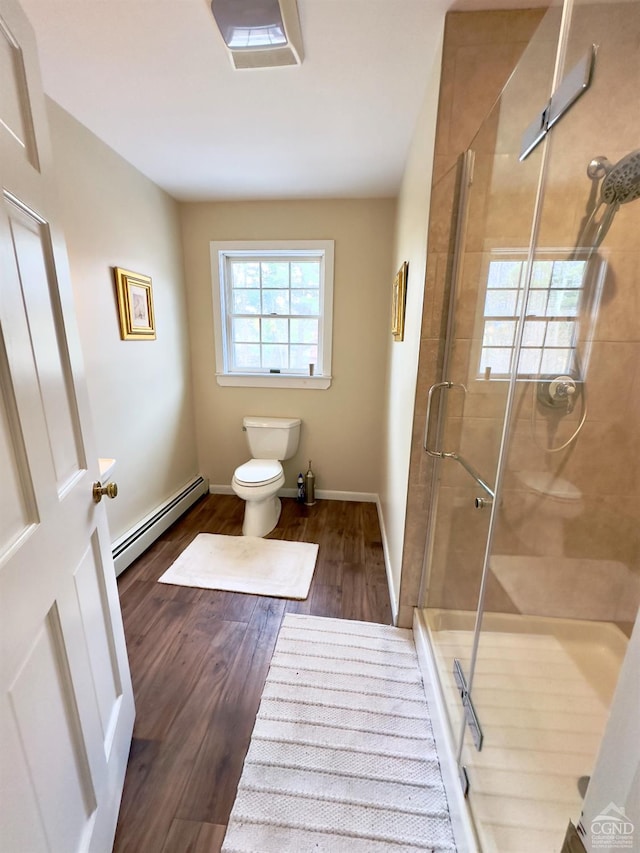 bathroom with wood finished floors, baseboards, a shower stall, a baseboard heating unit, and toilet