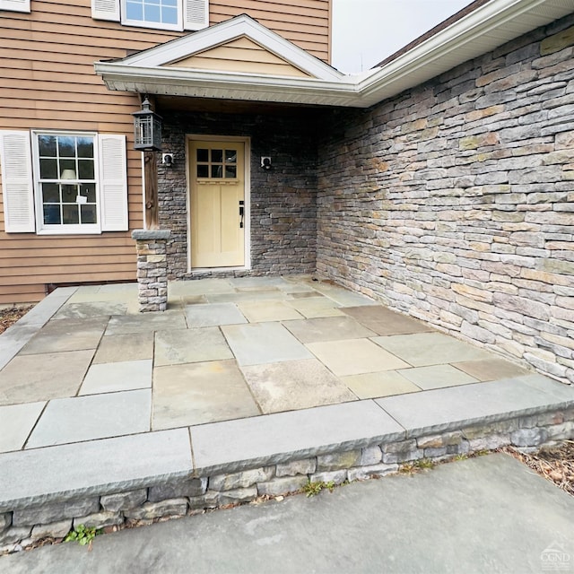 doorway to property featuring a patio area and stone siding