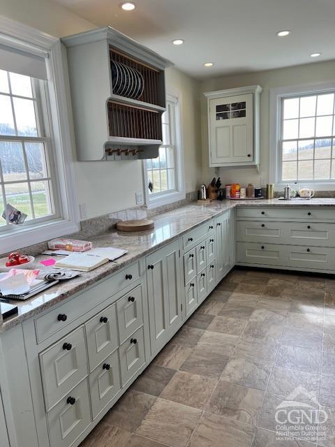 kitchen featuring recessed lighting, light stone countertops, and white cabinetry