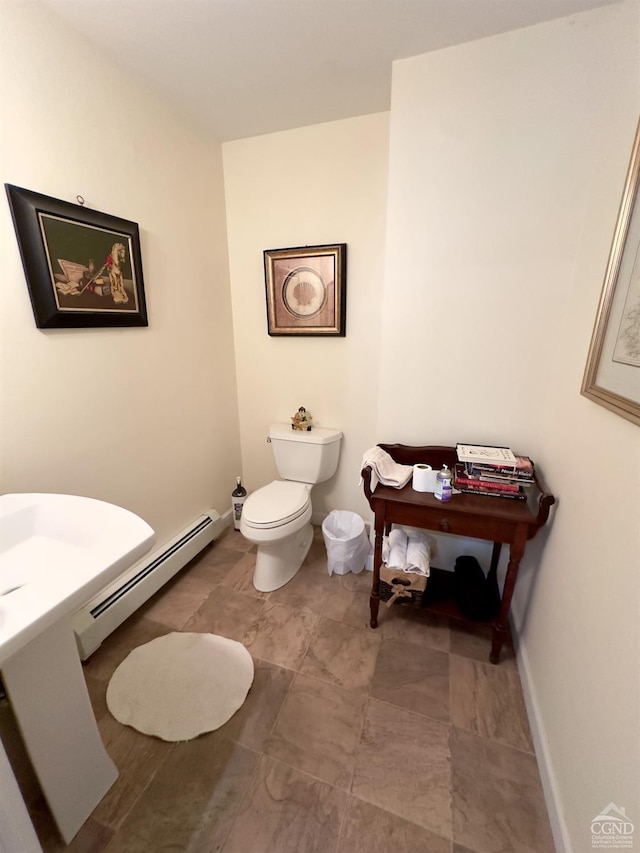 half bath with toilet, baseboards, and baseboard heating