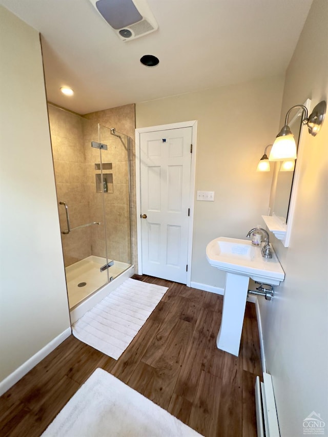 bathroom with recessed lighting, a stall shower, baseboards, and wood finished floors