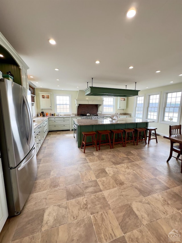 kitchen featuring baseboards, a breakfast bar, light countertops, recessed lighting, and freestanding refrigerator