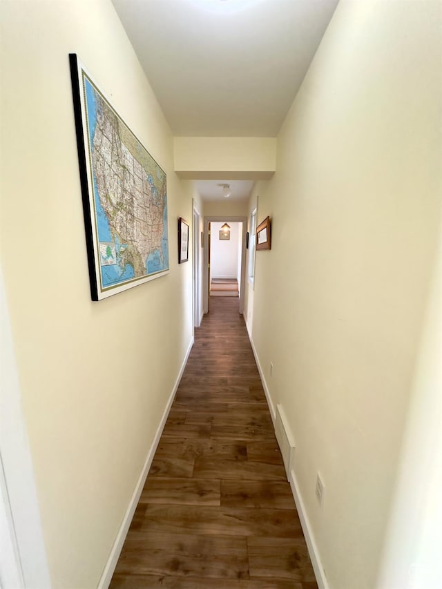 hallway featuring visible vents, dark wood-type flooring, and baseboards