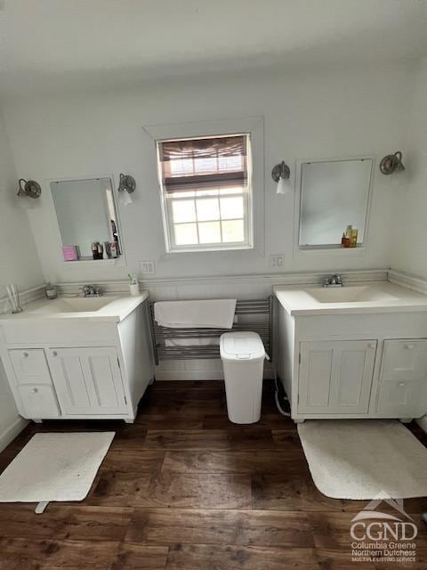 bathroom with a sink, wood finished floors, and two vanities