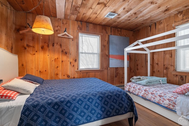 bedroom featuring visible vents, wood ceiling, multiple windows, and wood walls