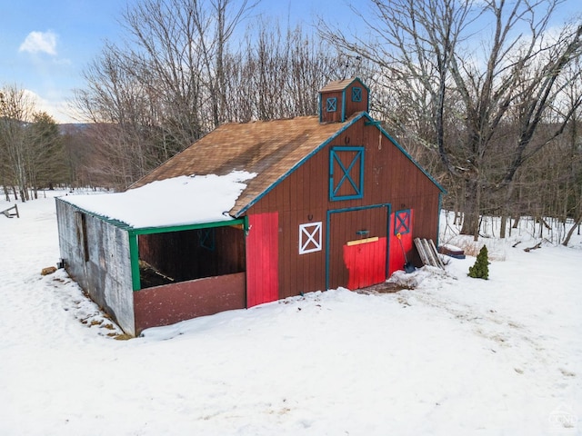 snow covered structure featuring a barn and an outbuilding