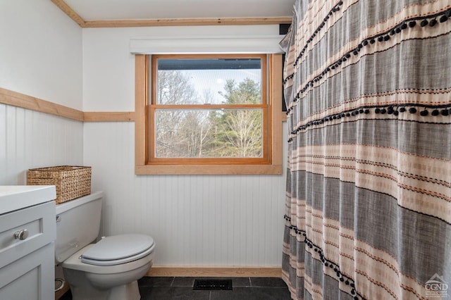 bathroom featuring vanity, tile patterned flooring, a shower with curtain, a wainscoted wall, and toilet