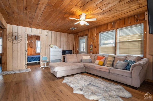 living room featuring wooden walls, visible vents, ceiling fan, and wood ceiling