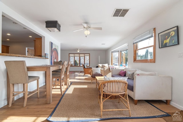 living room featuring light wood finished floors, baseboards, a ceiling fan, and visible vents