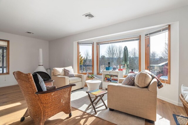living area featuring a healthy amount of sunlight, light wood finished floors, baseboards, and visible vents