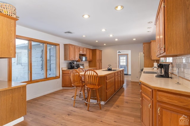 kitchen with light countertops, a kitchen island, visible vents, appliances with stainless steel finishes, and light wood finished floors