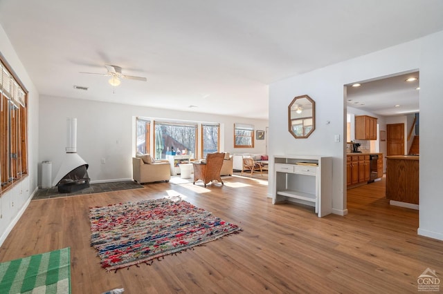 living room with light wood-style flooring, ceiling fan, and baseboards