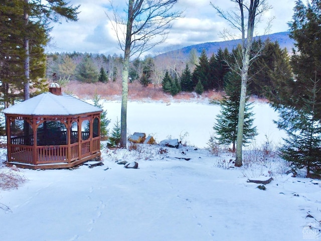 yard covered in snow featuring a mountain view and a gazebo