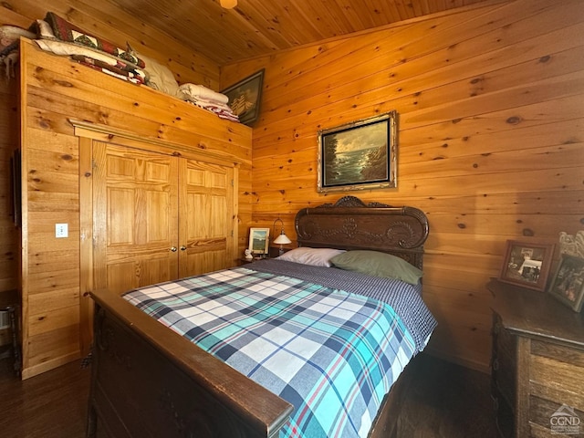 bedroom with a closet, wood ceiling, and wooden walls