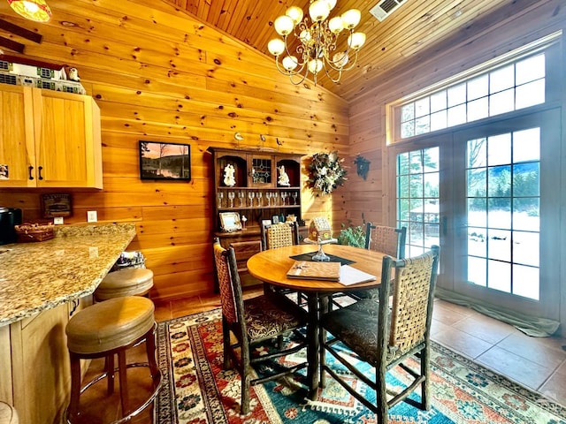 dining room with wooden walls, a chandelier, vaulted ceiling, wooden ceiling, and light tile patterned floors