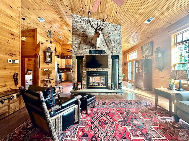 living room featuring a fireplace, wood walls, hardwood / wood-style floors, a high ceiling, and wood ceiling