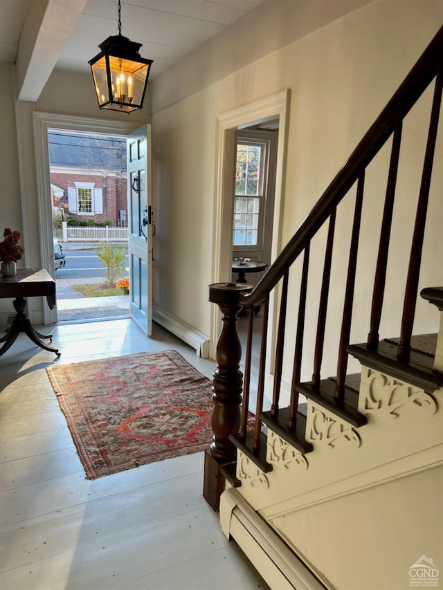 foyer with light wood-type flooring, a baseboard radiator, and a chandelier