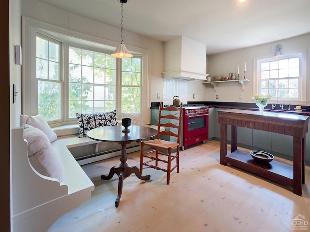 kitchen with hanging light fixtures, a baseboard heating unit, premium range hood, breakfast area, and light wood-type flooring