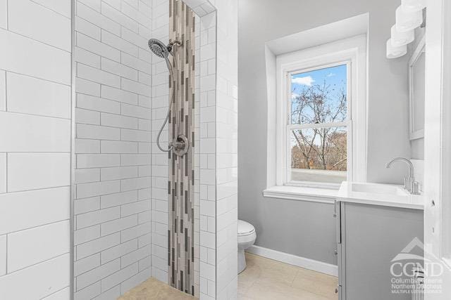 bathroom with tile patterned flooring, toilet, a tile shower, and vanity