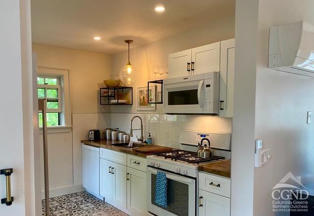 kitchen featuring butcher block counters, white appliances, sink, decorative light fixtures, and white cabinetry