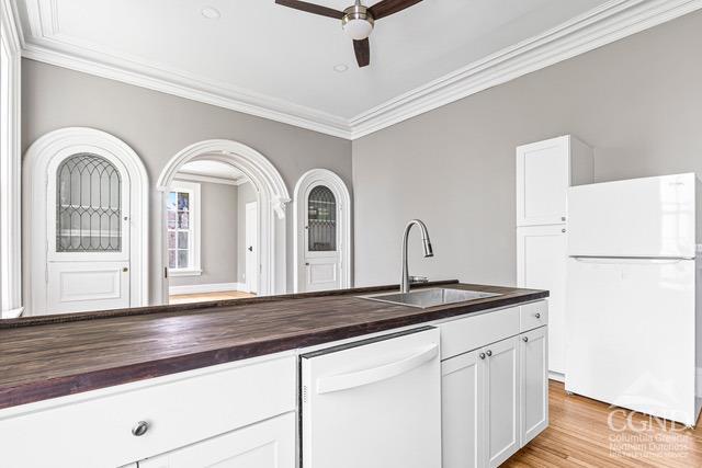 kitchen with white cabinetry, sink, ceiling fan, butcher block countertops, and white appliances