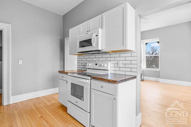 kitchen featuring white cabinets, tasteful backsplash, white appliances, and light hardwood / wood-style flooring