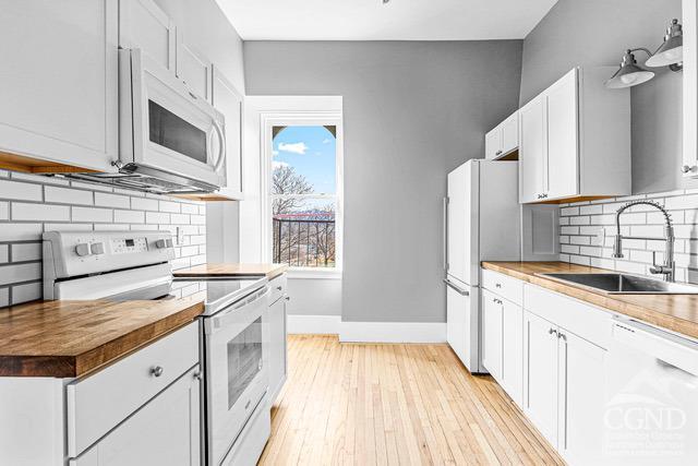 kitchen featuring light wood-type flooring, tasteful backsplash, white appliances, sink, and white cabinets